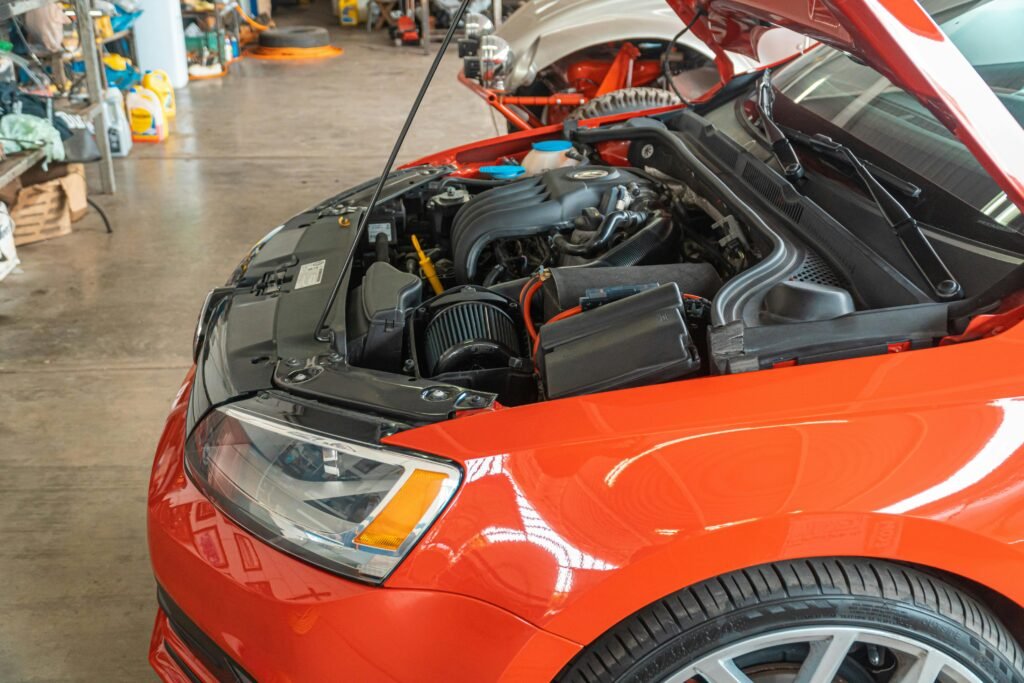 Detailed view of a red car's engine bay in an automotive workshop highlighting repair and maintenance.